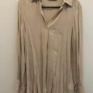 Beige skjorta från Defacto - Säljer en beige skjorta från Defacto Modest. Skjortan har klassisk krage, knäppning framtill och långa ärmar med knappar vid ärmslut. Perfekt för en stilren och enkel look. Den är skrynklig då den legat i garderoben, stryks om så önskas vid köp! Kan gå ner i pris vid snabb affär!💕