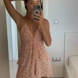 Zara klänning sommar - Söt ljusrosa kortklänning med blommigt mönster och tunna axelband. Djup v-ringning framtill och luftig passform, perfekt för varma dagar. Klänningen har en lätt och somrig känsla.