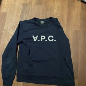 Marinblå sweatshirt från A.P.C. - Säljer en marinblå sweatshirt från A.P.C. med stor vit logotyp på framsidan. Storlek Xs. Passar 16-172
