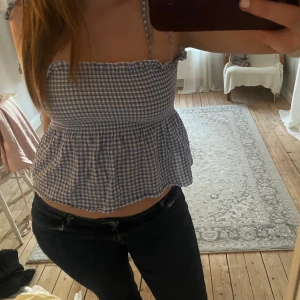 Blåvit rutig top - Säljer en söt blåvit rutig topp med smockad överdel och volang nertill. Toppen har tunna axelband och är perfekt för varma dagar. M men mer som en S. 