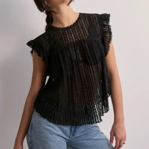 Svart transparent blus med volangärmar - Säljer en svart blus från Nelly med volangdetaljer på ärmarna och knytning i nacken. Använd fåtal gånger. 