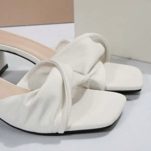 Vita klackade sandaler med rosett - Säljer ett par trendiga vita sandaler med fyrkantig tå och bred klack. Skorna har en fin dekorativ framsida och öppen häl. Perfekta för dig som vill ha en stilren och modern look. Nypris, ca200kr