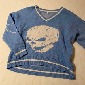 Stickad tröja - Säljer en blå stickad tröja med döskalle på framsidan och hjärtdetalj på ärmen. Hör av dig om du undrar något🩷