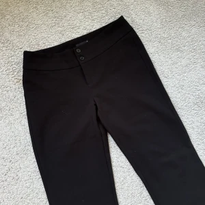 Svarta kostymbyxor från Gina Tricot - Svarta kostymbyxor från Gina Tricot med två knappar i midjan och rak passform. Midjan är under naveln. Inte använda mer än kanske 5 ggr, bra skick❣️