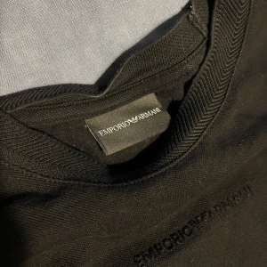 Svart t-shirt från Emporio Armani - Säljer en stilren svart t-shirt från Emporio Armani. T-shirten har rund halsringning och diskret broderad logga framtill. Perfekt för dig som gillar klassiska och enkla plagg med exklusiv känsla. Nypris: 1600kr