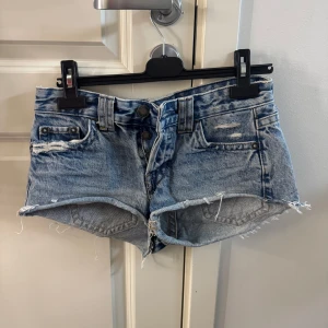 Blå jeansshorts från Pull&Bear - Säljer ett par ljusblå jeansshorts från Pull&Bear med fransiga kanter och slitna detaljer. De är lågmidjade. Shortsen har fem fickor och knäppning ifram. Jag säljer de då de blivit för små. De är i mycket bra skick endast använda ett par gånger. 