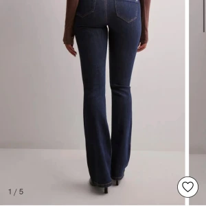 Mörkblå bootcut jeans - Säljer ett par mörkblå jeans med bootcut passform och klassiska fickor bak. Jeansen har hög midja och är tillverkade i ett stretchigt denimtyg som sitter snyggt över höfterna och låren innan de blir vidare nertill.