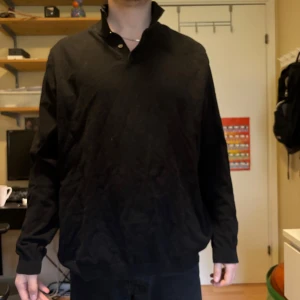 Svart långärmad tröja med piké  - Säljer en svart långärmad tröja med piké och knappar. Tröjan har en normal passform och är perfekt för dig som gillar en stilren och enkel look. Passar till det mesta och är riktigt skön att bära.