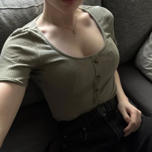 Ribbad topp - Ribbad grön topp. Snygg urringning och figurnära passform.