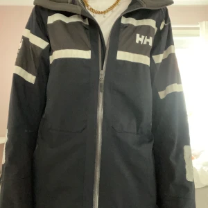 Vind/ regn jacka  - Cool jacka som skyddar mot regn och vind. NYPRIS 3 000. Är i färg mörkblå med detaljer. Är från Helly Hansen. Är i super bra skick och nästan aldrig använt. Skriv vid frågor. Pris går att diskutera.