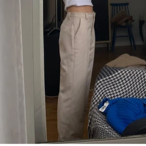 Lågmidjade loosefit kostymbyxor  - Lågmidjade, ljusa, loosefit kostymbyxor från NAKD i strl 40. I tjockare tyg. Jag tycker dom sitter perfekt på mig som är strl 38. Inga fläckar eller missfärgningar. Använda fåtal gånger. Nypris 599kr