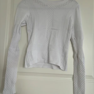 Vit stickad tröja från H&M - Säljer en vit stickad tröja från H&M med fina stickade detaljer och mönster. Tröjan har lång ärm och rund halsringning. Perfekt för lager-på-lager och passar till många olika stilar.