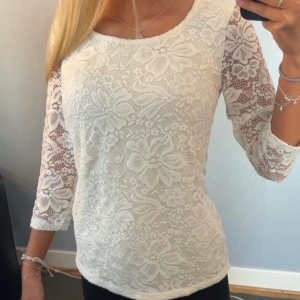 Vit spetsblus med trekvartsärm - XS/S Säljer en vit blus i spets med stora blommönster och trekvartsärmar. Knappast använd.