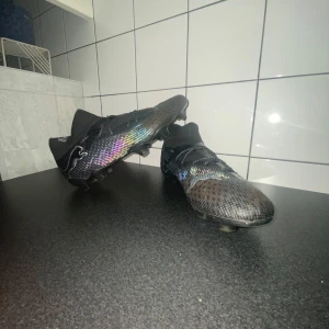 Svarta Puma Future PRO 8 Fotbollsskor - Säljer ett par svarta fotbollsskor från Puma med stickad överdel för att få maximal bekvämlighet. Skon har snörning och sitter mjukt runt foten. Säljer för att dem är för små. Använda i cirka två månader. Skon fungar för både gräs och konstgräs. Insidan av skon är vadderad så den är väldigt mjuk inuti.