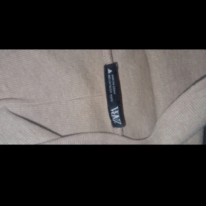 Beige polotröja från ZARA - Säljer en beige polotröja från ZARA i mjukt material. Tröjan har lång ärm och hög krage, perfekt för lager-på-lager eller som den är. Enkel och stilren design som passar till mycket.