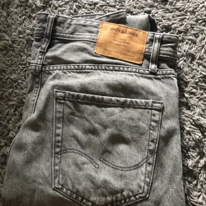 Grå jeansbyxor från Jack & Jones - Säljer ett par grå jeans från Jack & Jones. Byxorna har en loose passform, klassisk femficksdesign och knappgylf. Perfekta för en avslappnad stil. Byxorna är i nyskick👊🏻🔥 strl 30