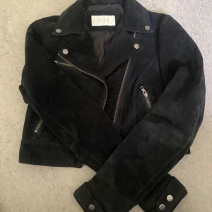 Svart skinnjacka från Vila - Snygg svart skinnjacka från Vila med klassisk bikerstil. Jackan har silvriga dragkedjor, knappar och detaljer samt krage med slag. Perfekt för att lyfta vilken outfit som helst. Köpt för typ 5-600. Passar S-M