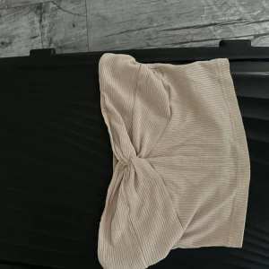 Beige ribbad tubtopp med knut - Säljer en beige ribbad tubtopp med snygg knutdetalj framtill. Perfekt för varma dagar och enkel att styla med både jeans och kjol. Superskön och trendig modell!andvänd 2 gånger + ni står för frakt