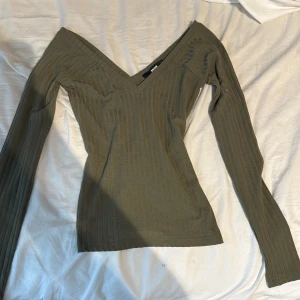 Olivgrön ribbad topp med v-ringning från Bik Bok - Säljer en olivgrön ribbad topp från Bik Bok i storlek XS. Toppen har lång ärm och djup v-ringning, perfekt för en trendig och stilren look. Materialet är stretchigt och sitter snyggt på kroppen. Den har bara testats aldrig använt. Säljer den pga att den inte passar oxh har därför ingen användning av den. Köparen står för frakt 💗