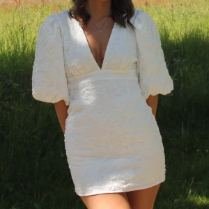 Snygg studentklänning  - Superfin vit kortklänning med djup v-ringning och puffiga kortärmar. Klänningen är perfekt till studenten. Från Showpo 