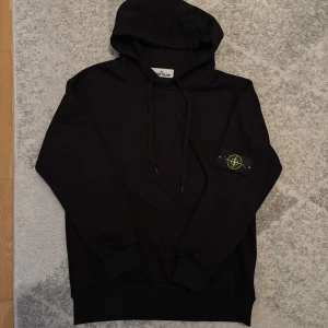 Svart hoodie från Stone Island - Säljer en svart hoodie från Stone Island. Knappast använd. Storlek m. Säljs pga att den bara står i garderoben och kommer inte till användning. 