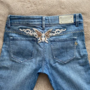 Ljusblå low waist jeans med fina detaljer - Så snygga jeans med coola detaljer💞 köpt second hand men är tyvärr för små för mig så har inte kommit till användning.   Midja: 38cm Innerbenslängd: 76cm