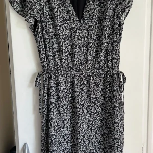 Svartvit blommig klänning från H&M - Säljer en svartvit klänning från H&M med blommigt mönster. Klänningen har korta volangärmar, v-ringning och knytband i midjan. Bara testat den. Passar xs-m då det går att knyta i midjan 