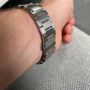 Silverfärgad klocka  - Snygg silverfärgad klocka med kvartsurverk. Den har en stilren mörkblå urtavla med dag- och datumvisning. Armbandet är i rostfritt stål och ger en elegant look. Perfekt för den som gillar en klassisk stil. PRIS KAN DISKUTERAS