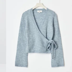 Trendig omlottkofta - Så fin o trendig knitted wrap cardigan från gina tricot. Perfekt till lite kyligare sommarkvällar!! Skonsamt använd o har inga defekter. Slutsåld i flera storlekar. Säljer en beige också.