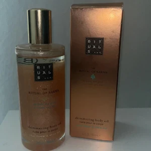 Rituals The Ritual of Karma Shimmering Body Oil - Shimmering body oil från Rituals i serien The Ritual of Karma. Kommer i en lyxig glasflaska med guldfärgat lock och tillhörande förpackning. Oljan har en skimrande effekt och doft av helig lotus och vit te.