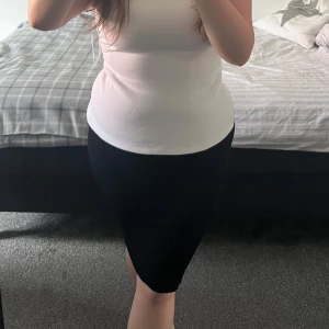 Svart ribbad kjol - Säljer en svart ribbad kjol med tight passform och stretchigt material. Kjolens längd kan justeras, den kan sitta längre eller kortare (beroende på vad man önskar). 