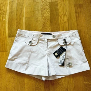 Vita shorts från Atos Lombardini - Snygga vita shorts från Atos Lombardini med fickdetaljer och knappar framtill. Låg midja, jag köpte fel storlek och har aldrig använt den. Det är italiensk storlek 44, vilket motsvarar M internationellt. Midjan är 42 cm och längden är 31 cm.Originalpris 248 euro.