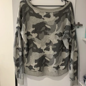 Grå camouflagemönstrad stickad tröja - Säljer en grå stickad tröja med camouflagemönster i olika nyanser av grått. Tröjan har lång ärm, rundad halsringning och en avslappnad passform. Perfekt för dig som gillar streetstyle och vill ha något bekvämt och snyggt.