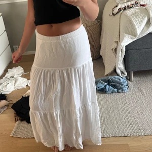 Vit långkjol med volang - Säljer en vit långkjol med volangdetaljer. Kjolen har en luftig och flowy passform, perfekt för varma dagar. Resår i midjan, kjolen är lite vriden på baksidan men det är inget som stör tycker jag