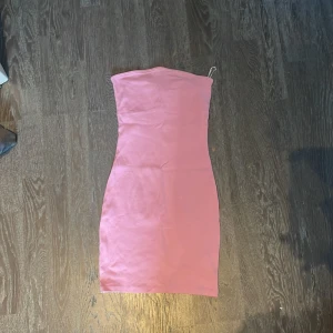 Rosa axelbandslös klänning - Säljer en enkel och stilren rosa axelbandslös klänning i ribbat material. Klänningen är tight och lagom kort, perfekt till stranden eller liknande