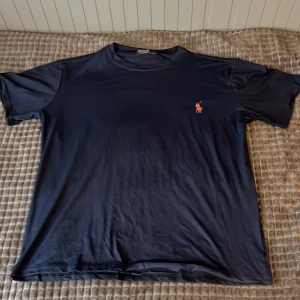Mörkblå t-shirt från Polo Ralph Lauren - Säljer en mörkblå t-shirt från Polo Ralph Lauren. Tröjan ligger i bra skick och nästan helt ny.