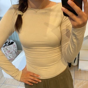 Beige långärmad topp - Säljer en beige långärmad topp i stretchigt bomullsmaterial. Har en rundad halsringning och går att vända back och fram och få en boatneck ringning. Framsidan är double lined. Super skönt material. Från bibok, använd en gång. Stl XS men passar mig i S/M