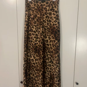 Leopardmönstrad långkjol från Neo Noir - Säljer en snygg långkjol från Neo Noir med leopardmönster. Kjolen har en rak och flowy passform och materialet känns mjukt och följsamt mot kroppen. Har använt den några gången men är fortfarande i superbra skick! 