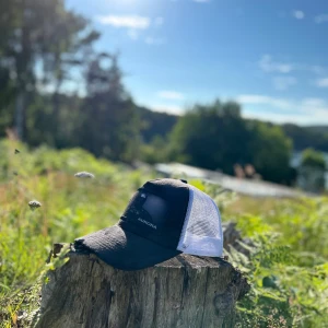 Svart och vit keps från Aurora - Snygg svart och vit keps från Aurora med mesh på sidorna och bak, samt böjd skärm. Framsidan har en svart lapp med tryck. Perfekt för soliga dagar och utomhusaktiviteter.