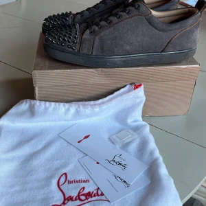 Mörkgrå sneakers med nitar från Christian Louboutin - Säljer dessa Louboutin eftersom att jag har skaffat nya skor. Pris är förhandlingsbart. Jag har storlek 44 men skorna skall passa någon med storlekar 44-46. Obs, högersulan har släppt lite men inget som märks.
