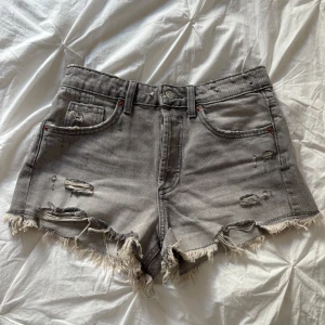 Grå jeansshorts från Zara - Grå jeansshorts med en sliten design från Zara i storlek 34. Endast använda ett fåtal gånger💕