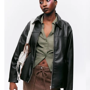 Svart skinnjacka med klassisk krage - Snygg svart skinnjacka med klassisk krage och raka linjer. Jackan har inte används och prislappen är kvar! Passar typ xs-m beroende på hur man vill ha den!