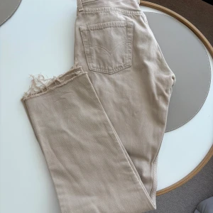 Beige Levis jeans - Säljer ett par beige Levis jeans med raka ben. Jeansen har en snygg rå kant nedtill och klassisk Levis-detalj på bakfickan. Jättefin beige färg. Står att det är storlek 30, skulle säga att det passar en S. 