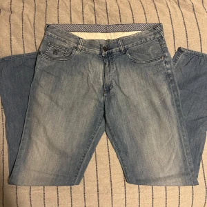 Canali Ljusblå jeans  - Snygga ljusblå jeans från Canali med klassisk femficksdesign och broderad logga på myntfickan. Jeansen har en rak passform och är tillverkade i mjukt denimtyg. Skinnpatch med Canali-märke baktill vid midjan ger en exklusiv touch.