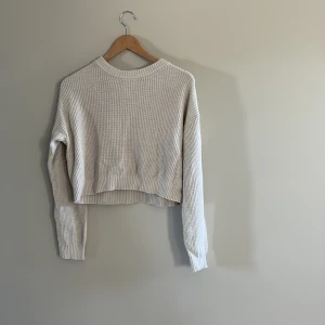 Beige ribbad stickad tröja Kappahl - Säljer en beige stickad tröja från Kappahl i ribbad modell. Tröjan har en croppad passform, rund hals och långa ärmar. 