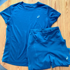 Blå/grönt träningsset från Asics - Blågröna Tights och T-shirt! Fina ihop eller var för sig. Tights med hög midja och snörning, även ficka för nycklar eller något annat litet. Litet hål på tightsen(bild 4). 180 för båda eller 90 per plagg.