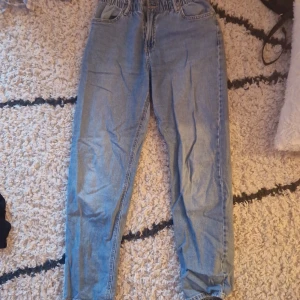 Blå jeans med resårmidja från Lindex - Säljer ett par ljusblå jeans från Lindex med resår i midjan och klassiska fickor både fram och bak. Jeansen har en relaxed fit och är perfekta för en chill och avslappnad stil. Materialet är mjukt denim och modellen är rak i benen.