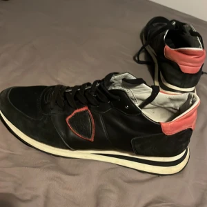 Philipe model tropez - Säljer ett par philipe models i svart med röda detaljer och vit sula. Skorna har snörning, rund tå och är tillverkade i skinn och mocka. Snygg kontrast mellan svart och rött, med klassisk Rockrunner-panel på sidan. Perfekta för dig som gillar exklusiva sneakers. Skorna har ingen innersula 