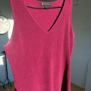 Vinröd ribbad linnetopp från INC - Vinröd linnetopp från INC med ribbad struktur och v-ringad hals. Toppen är ärmlös och har en fin passform som sitter skönt mot kroppen. Perfekt till hösten!