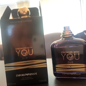 Emporio Armani Stronger With You Oud 90ml - Exklusiv parfym från Emporio Armani, Stronger With You Oud. Flaskan är mörklila med gulddetaljer och rund guldfärgad kork. Doften är intensiv och lyxig med oud-toner. Kommer i elegant svart och guld förpackning, 100 ml Eau de Parfum.